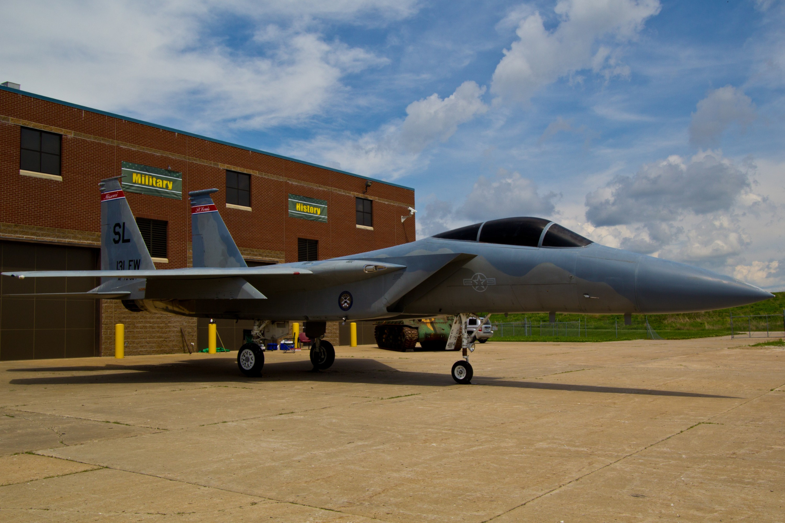 A military plane sits on the tarmac outside of a Military History building.