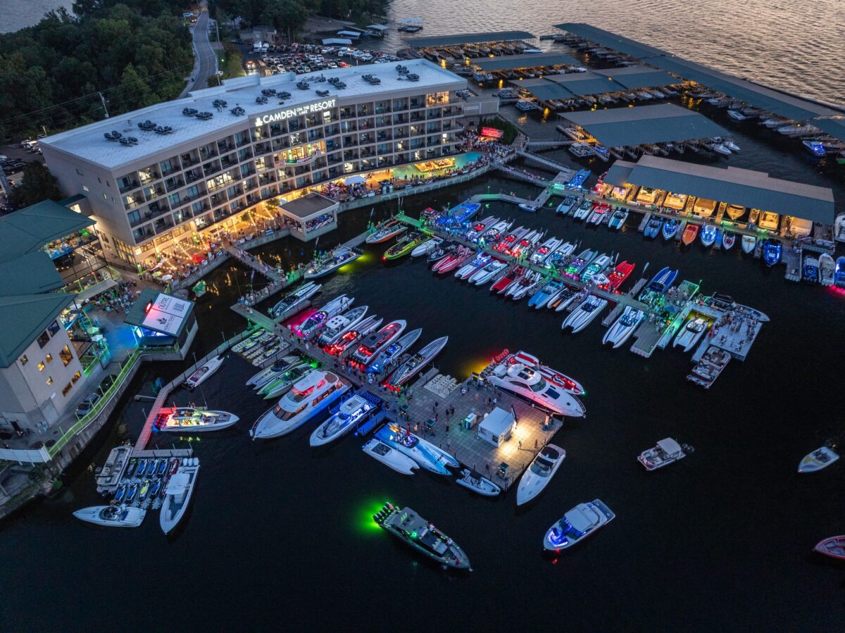 An aerial view overlooks Camden on the Lake Resort during dusk. Boats are illuminated with different bright colors fill the harbor and lights from the resort shine into the dark.