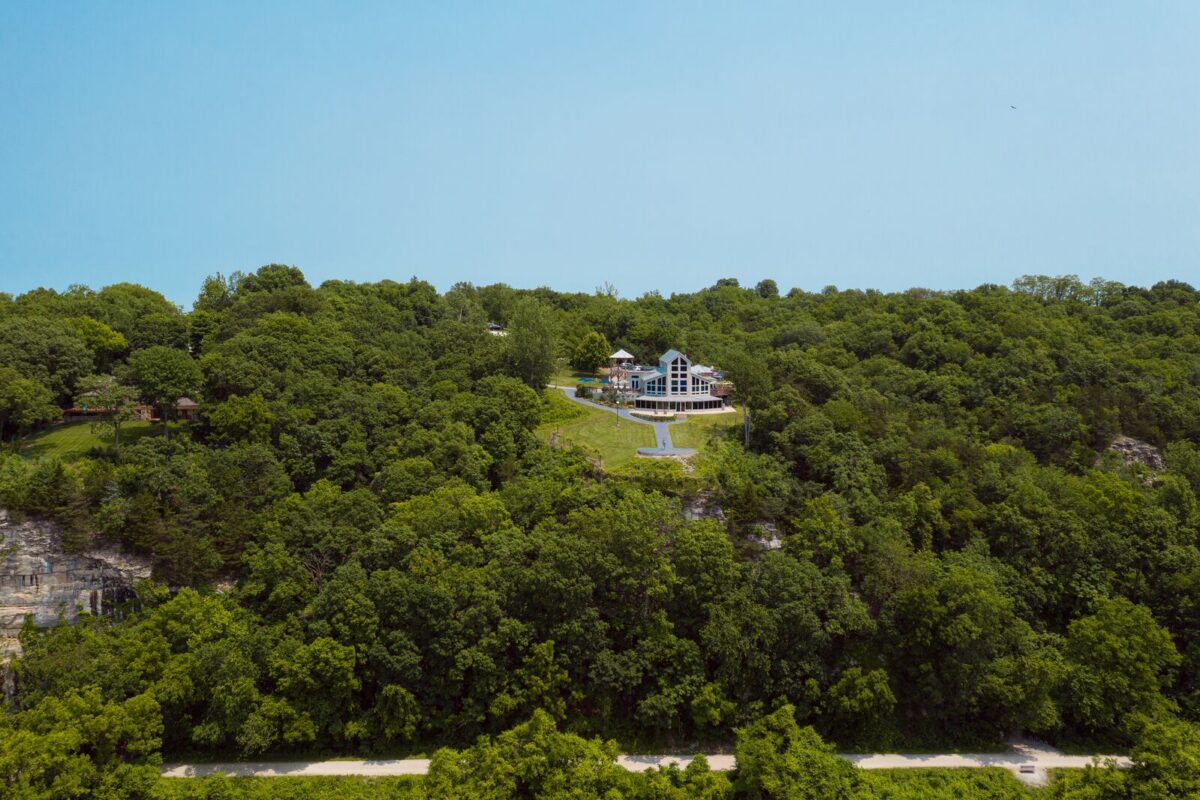 A building sits at the top of a bluff with a trail at the bottom of the bluff.