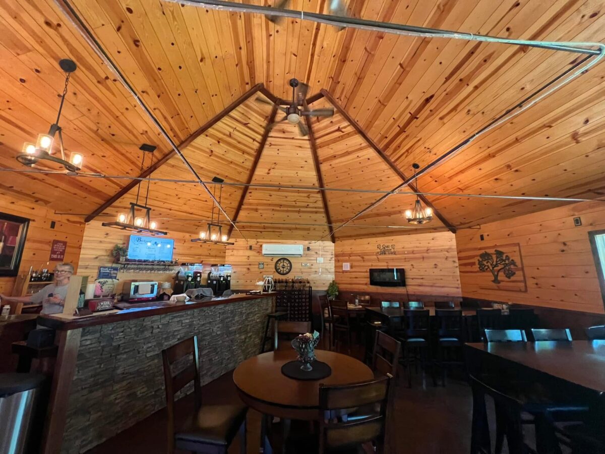 The interior of a winery, with a tall, pointed ceiling and tables and bar set.