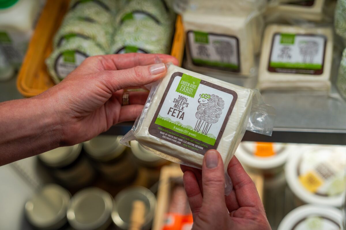 A person holds a block of freshly packaged cheese.
