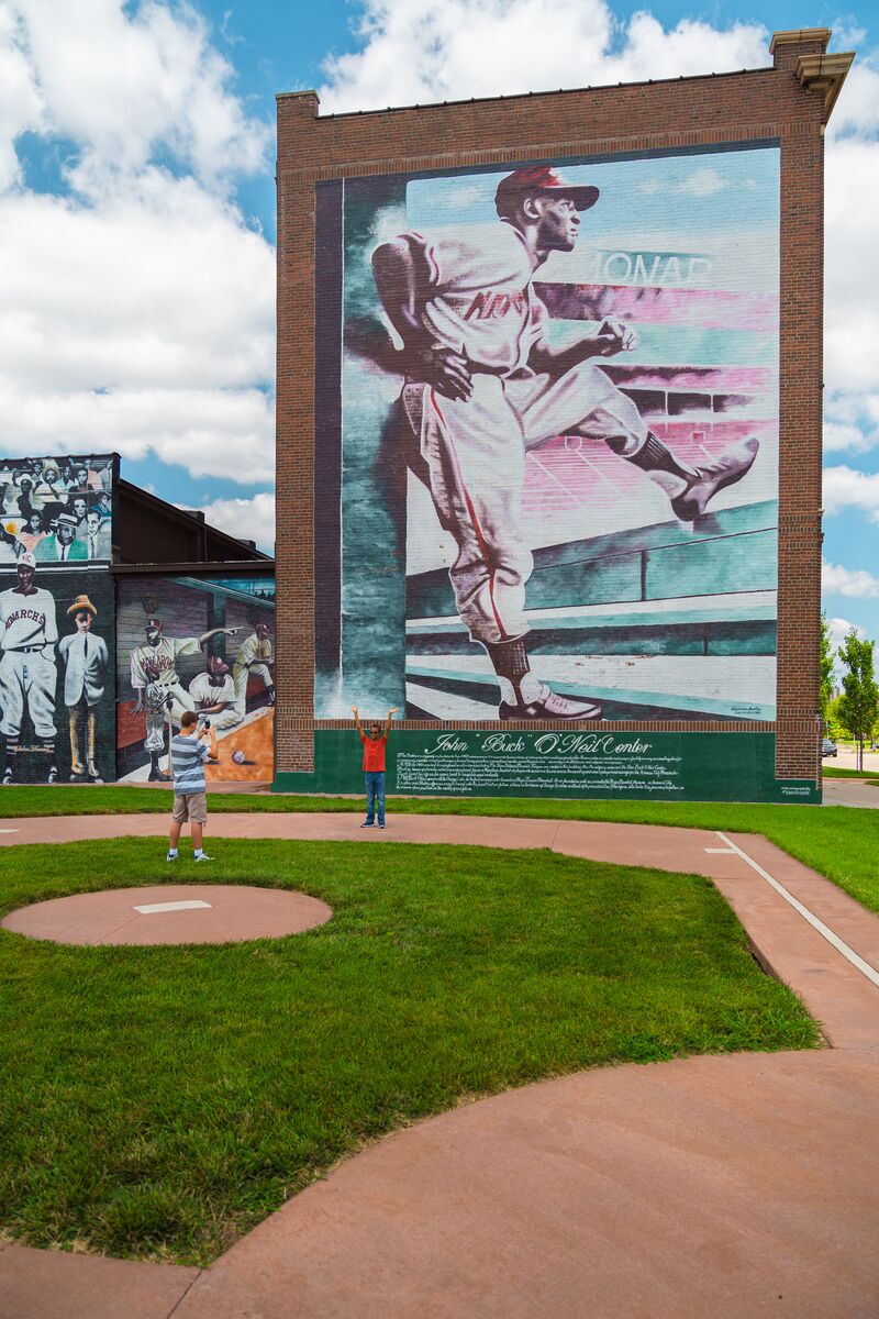 Children pose for photos in front of the Buck O' Neil tribute mural at a park in Kansas City, Missouri, celebrating the legend of this famous Missourian.