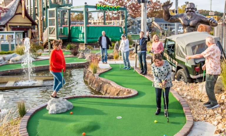 Several people play minigolf on a course.