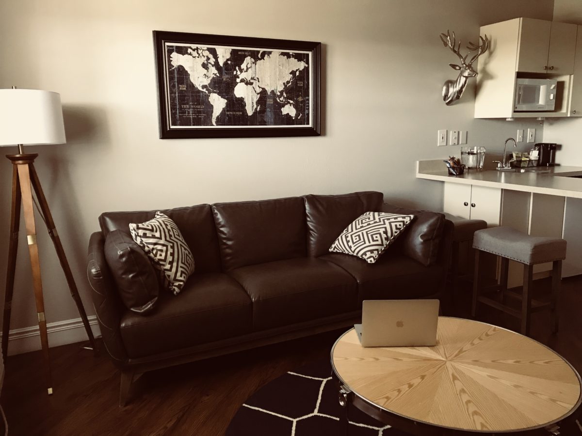 A living room with a brown leather couch and other furnishings.