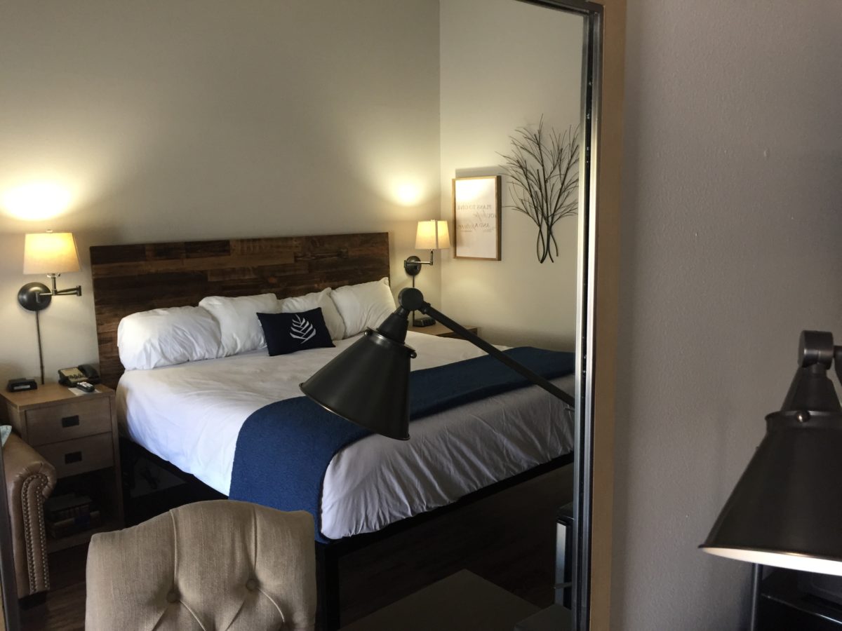 A made bed as seen reflected in a mirror.
