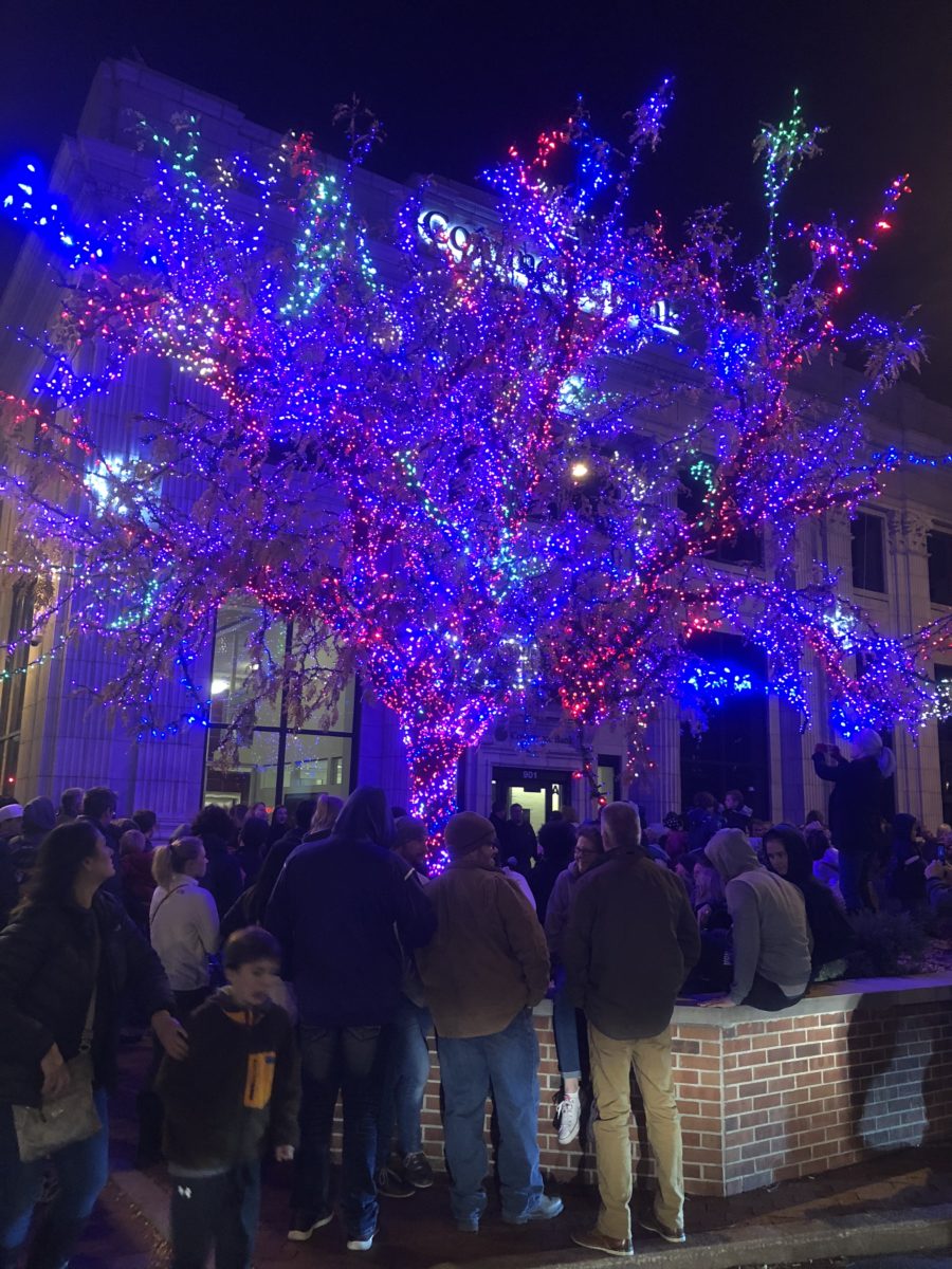 People gathered around a lit holiday tree.