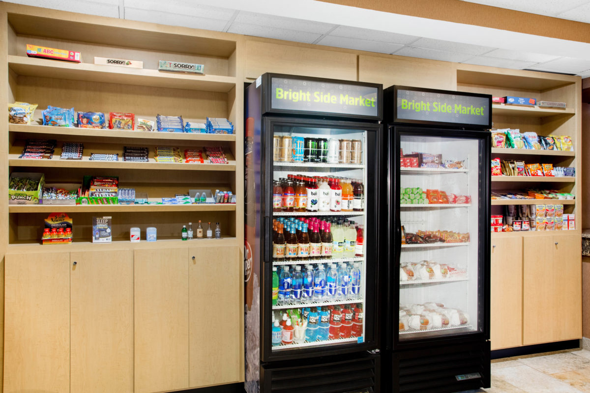 A fridge and stocked shelves in a market room.