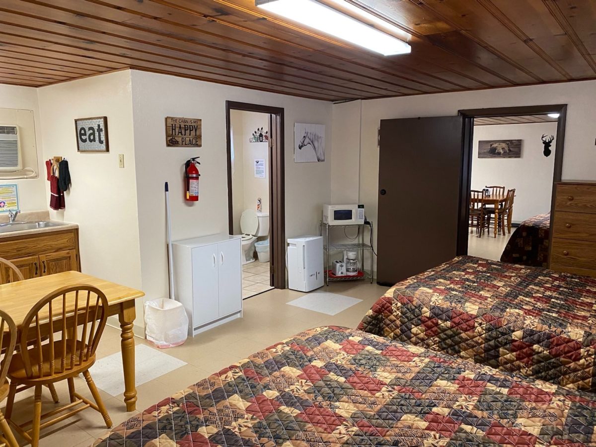 A furnished room in a cabin with two beds and a table/chairs.