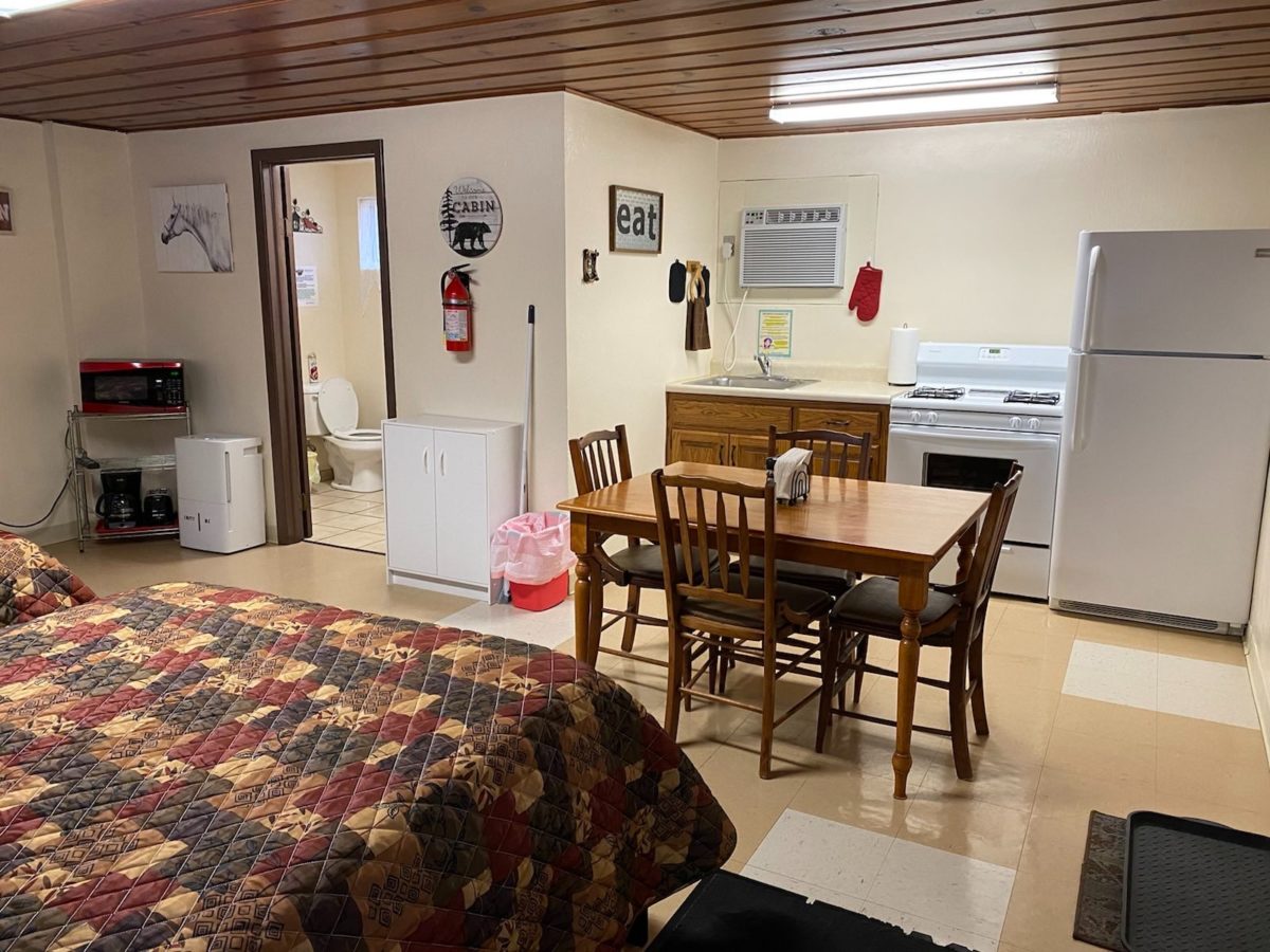 A furnished room in a cabin with two beds and a table/chairs.