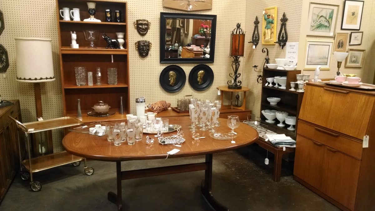 A booth at a relic center with a table and other furniture, and glassware.