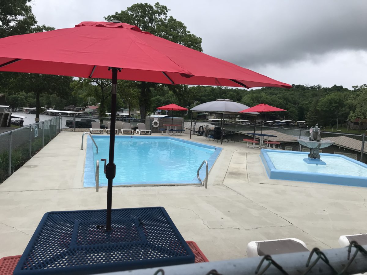 A red table umbrella near a pool.