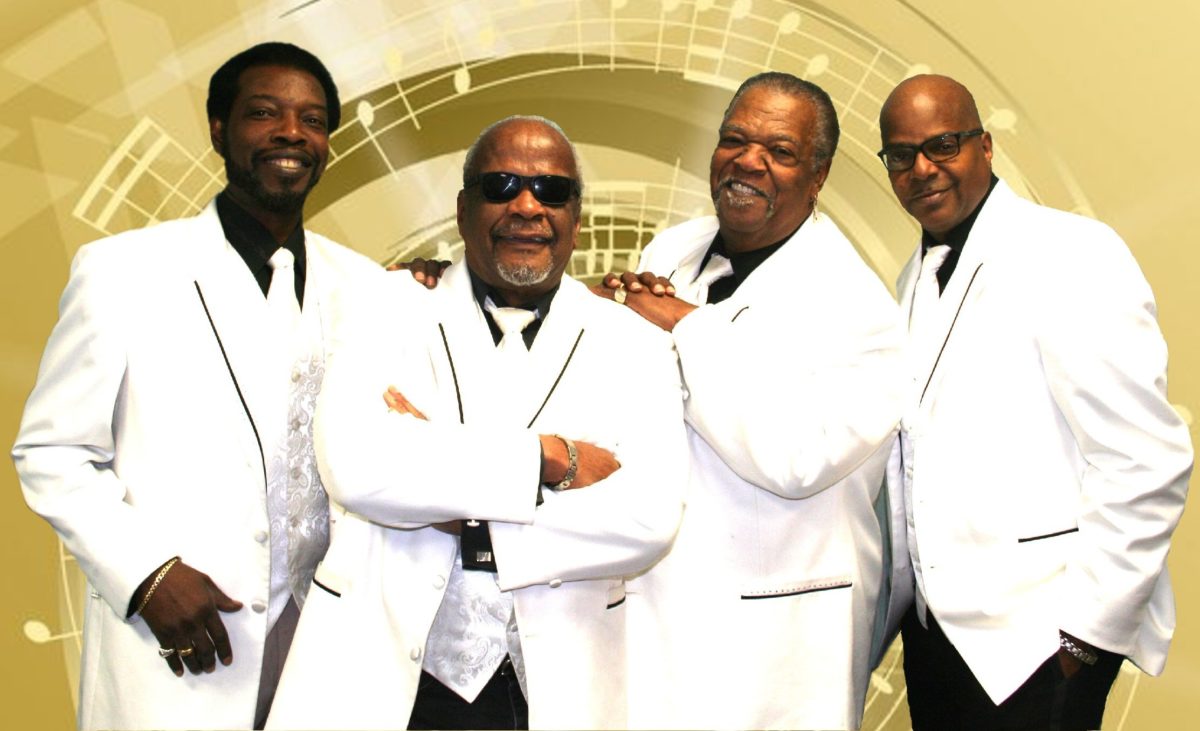 Four men in white suit jackets pose in front of a golden background.