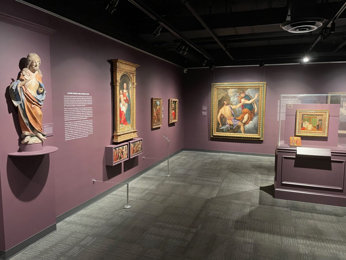 A display of artifacts of and pictures line maroon-colored walls at the Museum of Art and Archeology on the MU campus.