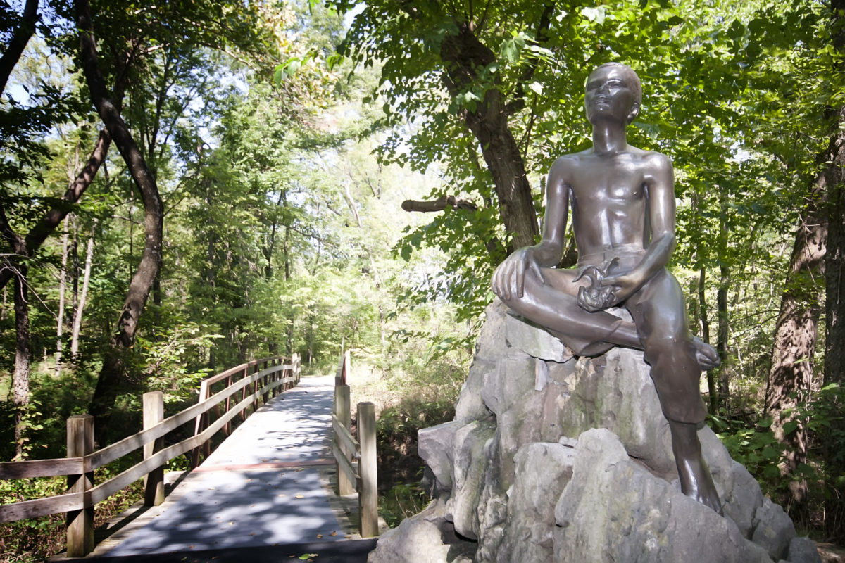 Bronze statue of young George Washington Carver holding a plant.
