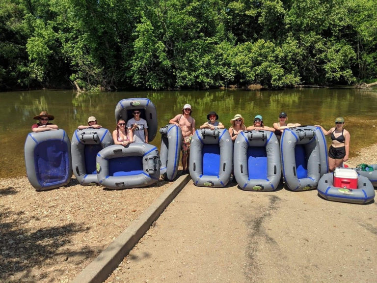 Several people with flotation devices at a body of water.
