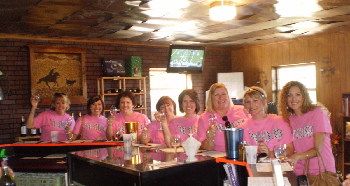 Several women posed together in a wine tasting room.