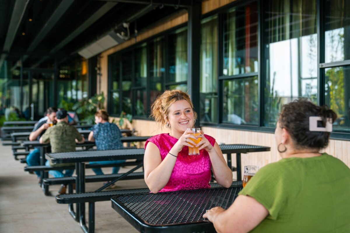 People sit on patio outside brewery and enjoy a beverage.