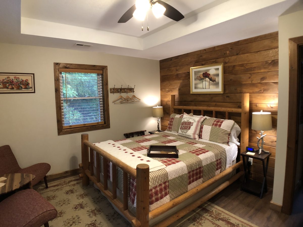 A rustic bedroom with quilts and wood paneling.