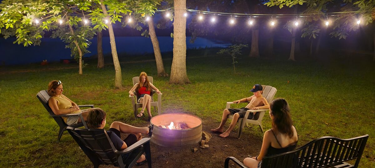 People sitting around a fire pit outdoors at night.