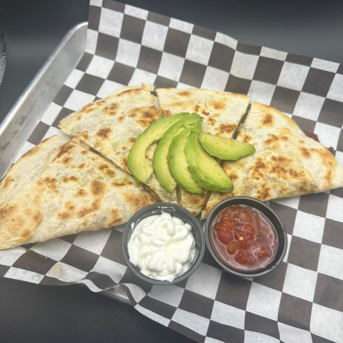 A Quesada plated with avocado and sauces.