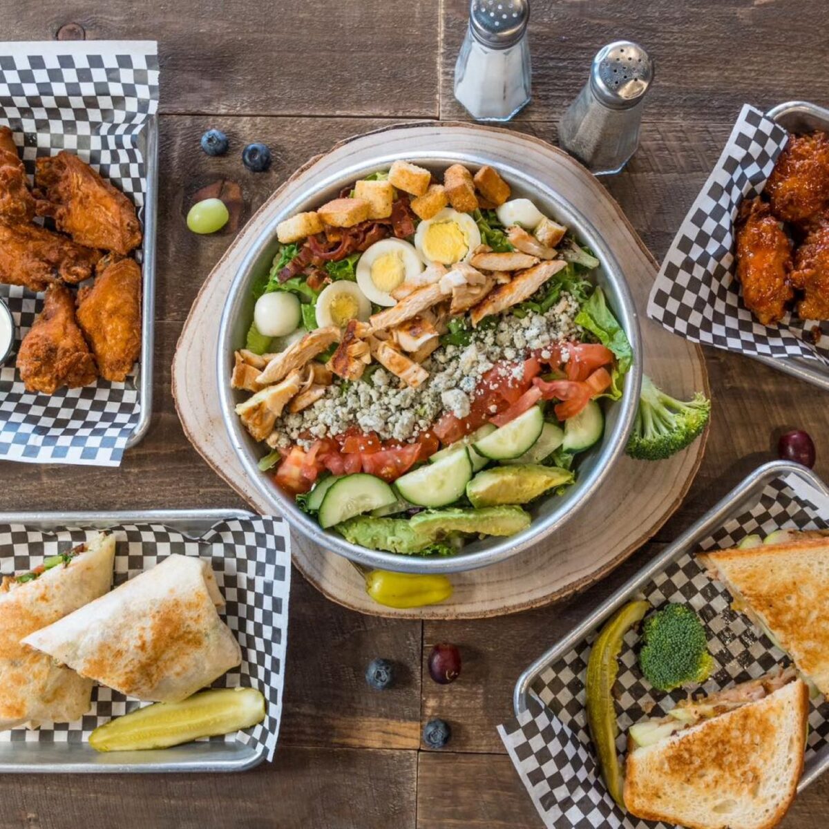 A plated salad and four other sides on a table.