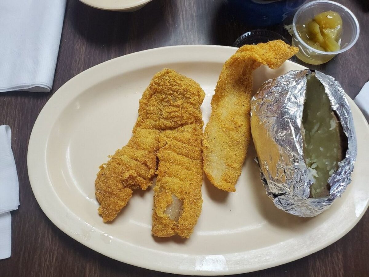 A plate of catfish and a baked potato.