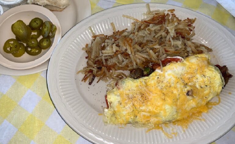 An omelet and hashbrowns plated with a side of peppers.