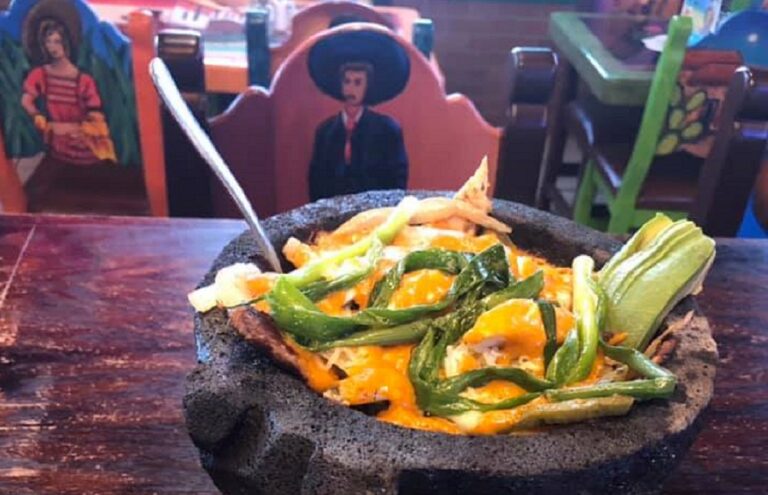 A dish at a Mexican restaurant in a deep black bowl on a wooden table.