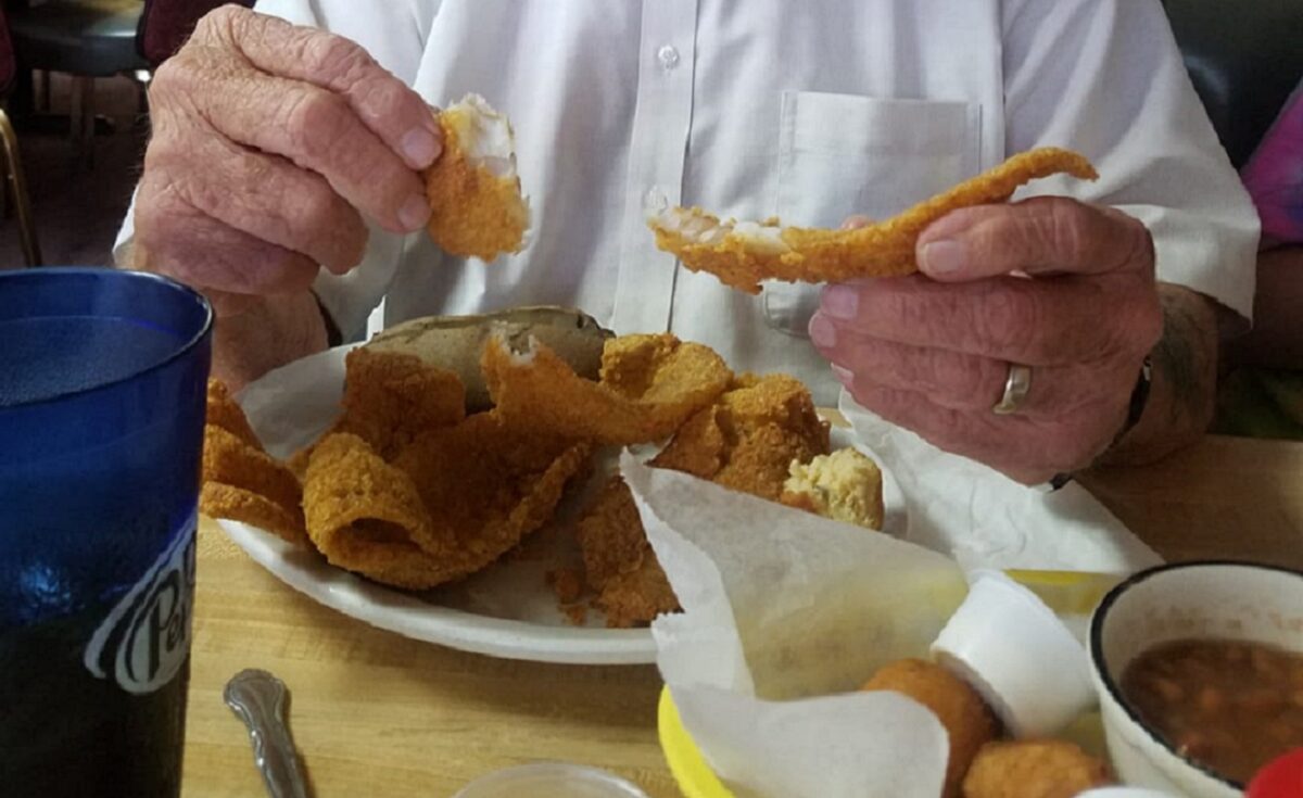 Someone eats fish from a plate.