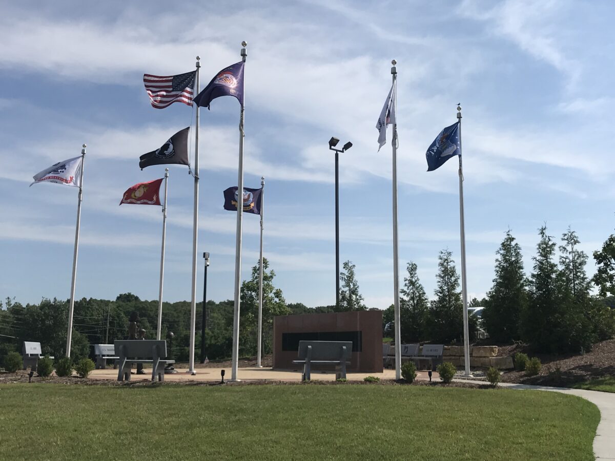 Various flags hoisted high as part of a veterans memorial.