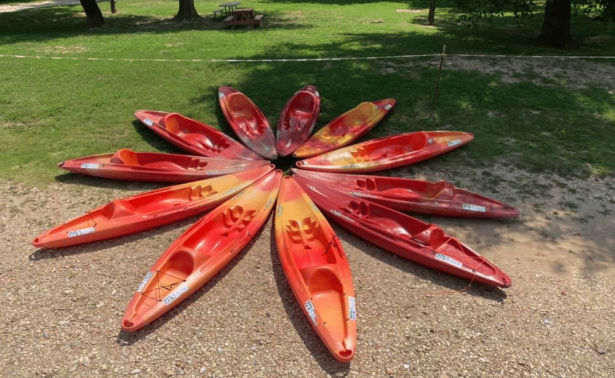 Several orange kayaks arranged together on the shore.