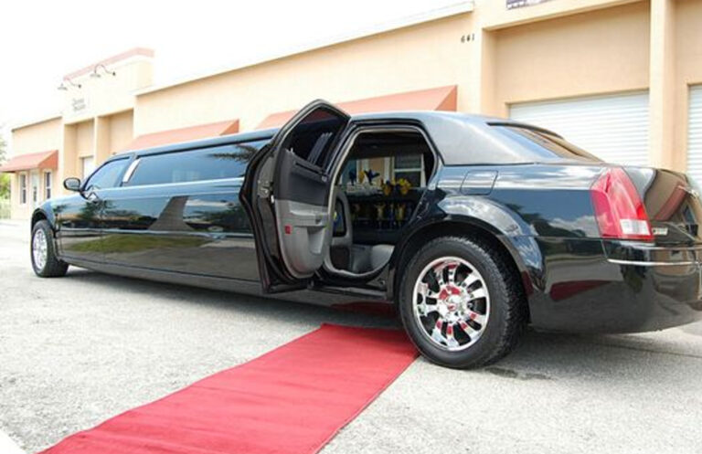 A limousine with an open door over a red carpet.