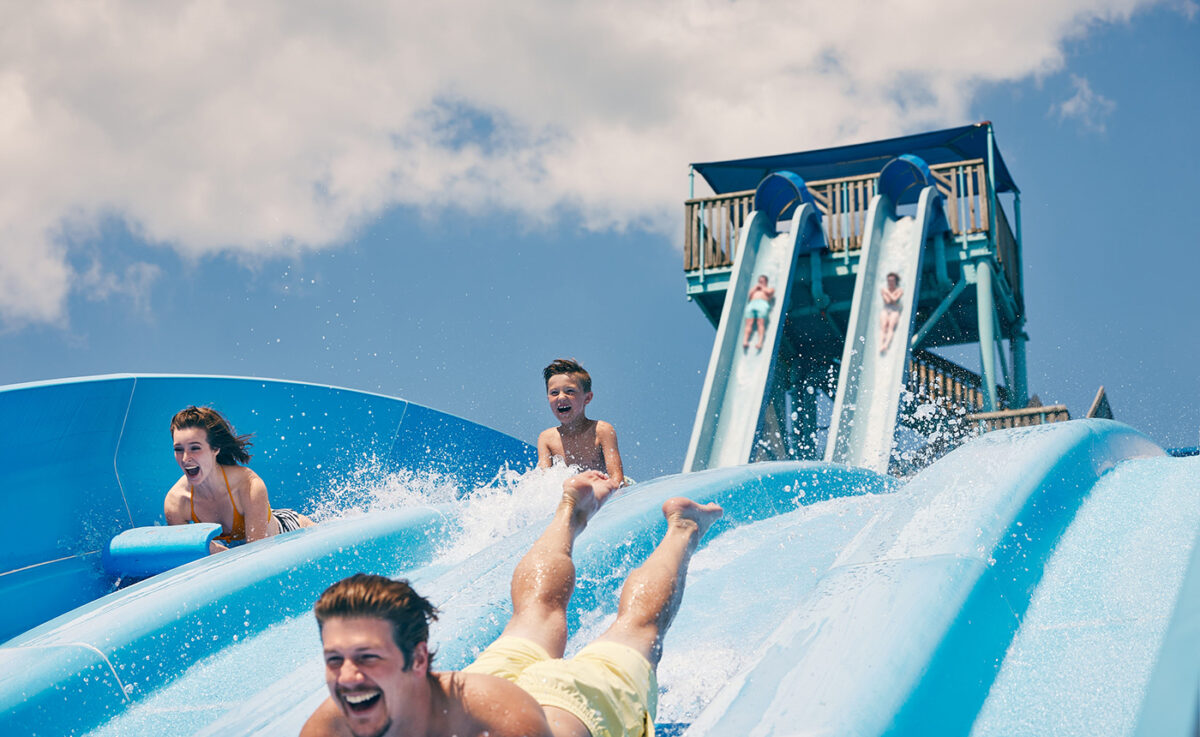 Three people go down the water slide with smiles on their faces at White Water.