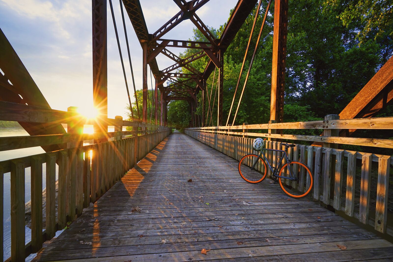 A bike sits leaning on the railing of a bridge.