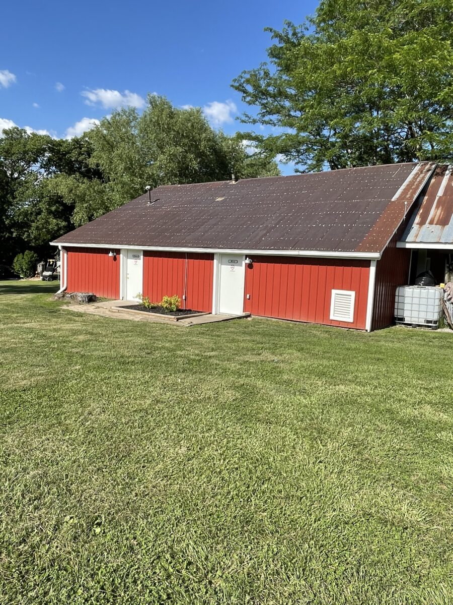The outside of a red building against a grass yard.