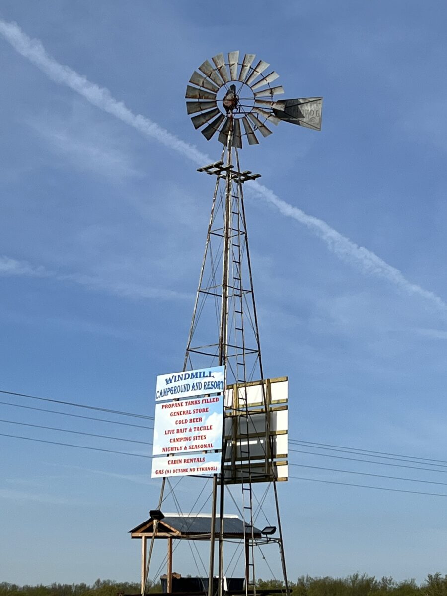 A windmill with signs against a blue sky.