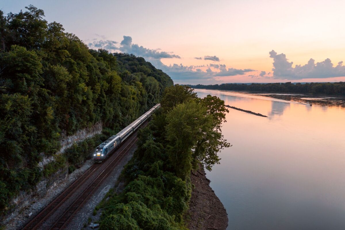 As the sun sets, a train travels along the tracks beside the Missouri River.