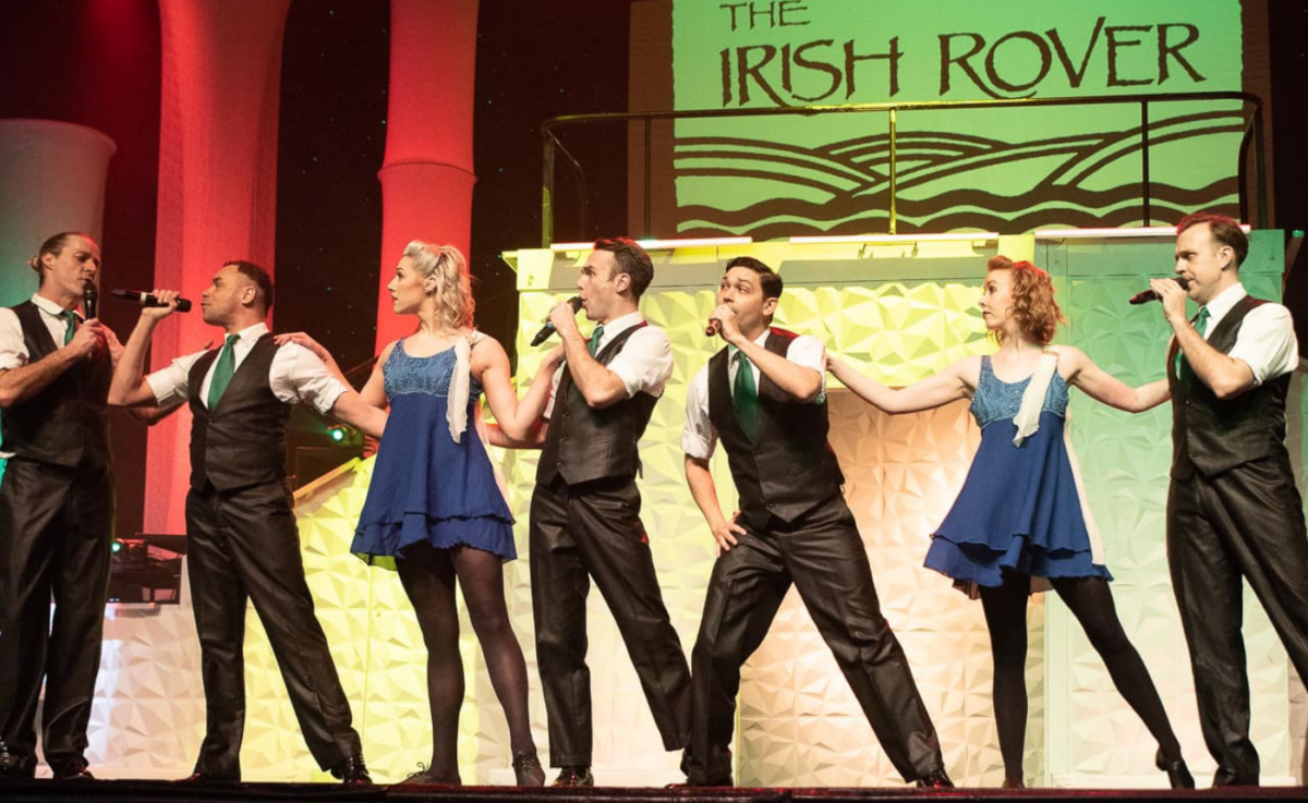 Seven people in Celtic dress perform on stage.