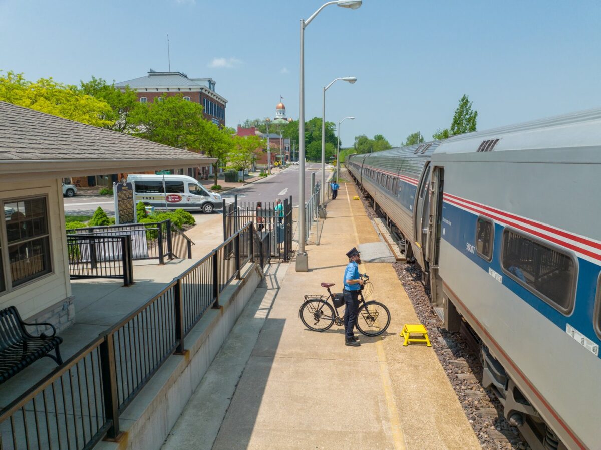 A person with a bicycle stands near a train.