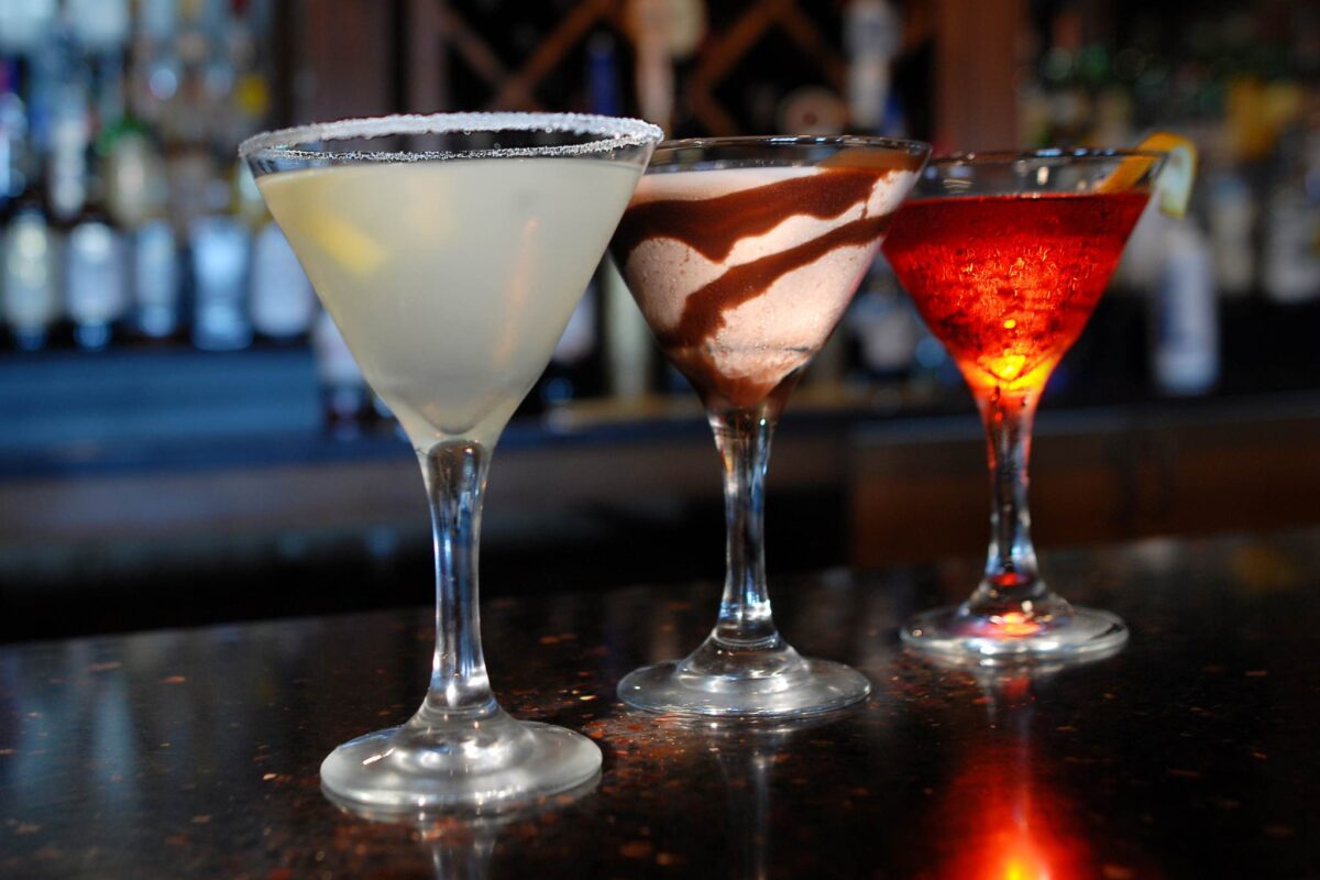 Three martinis on a bartop.