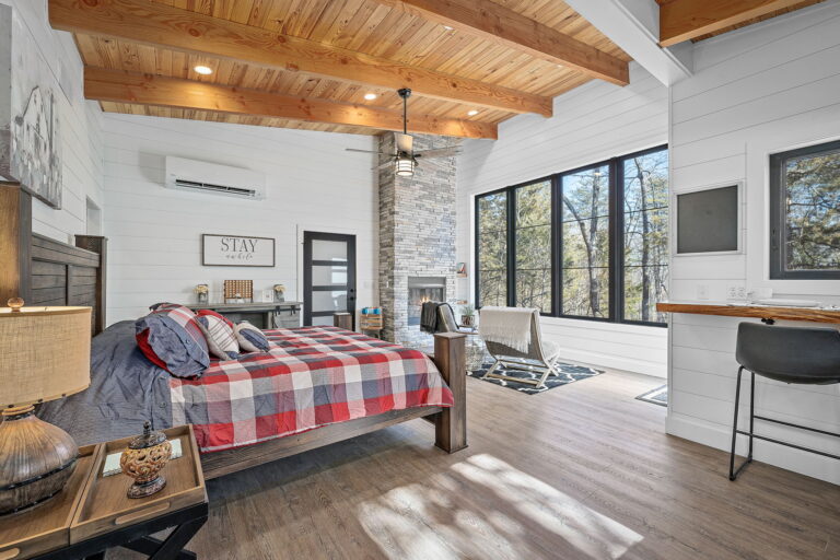 The interior of a treehouse bedroom with a large bed and picture window.