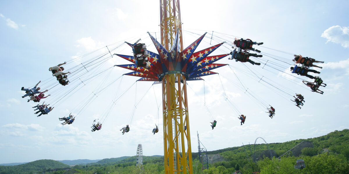 People ride an amusement park ride that is swings lifted into the air.