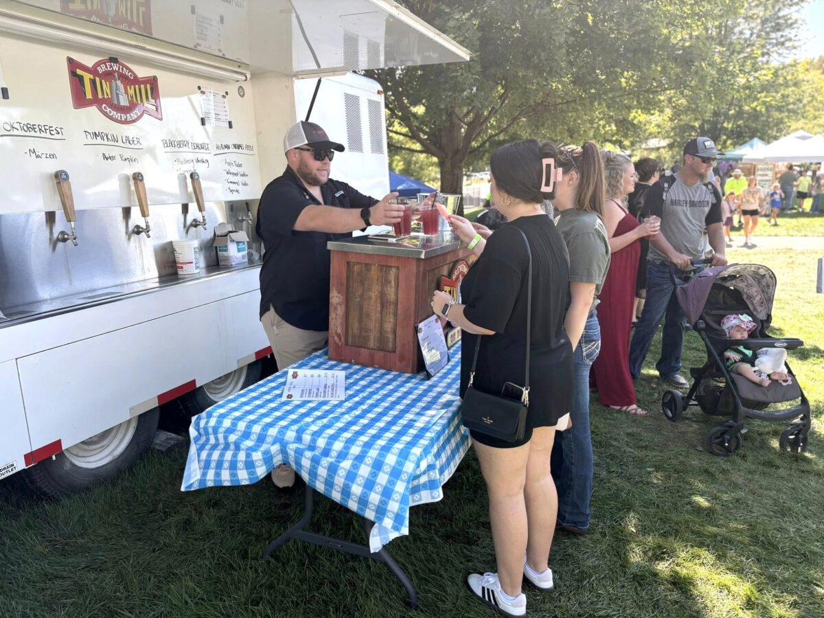 Attendees of a fall festival outside around a seller.