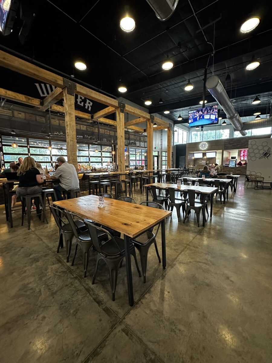 Several tables with chairs inside of a large food hall.