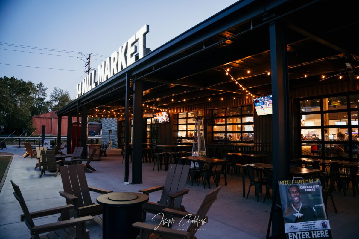 Several tables with chairs outside of a large food hall.