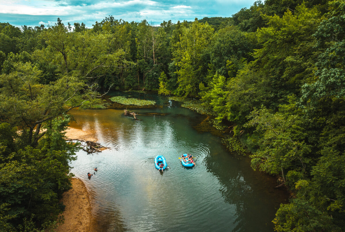 Aerial view of a body of water with boats surrounded by trees.