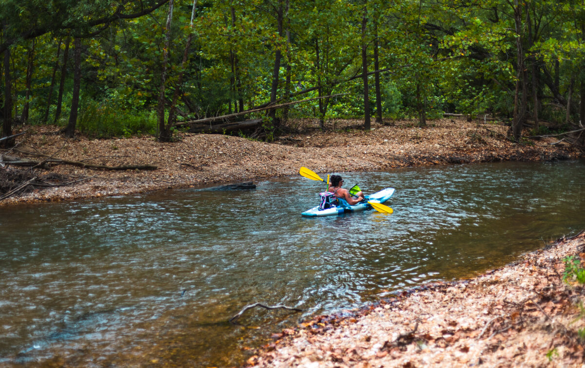 A person kayaks along a river.