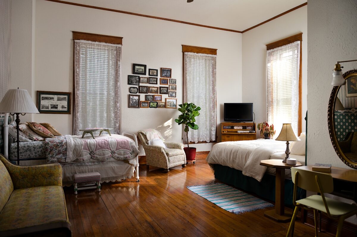 Spacious room with wood flooring, antique decor, and a king and a twin sized bed