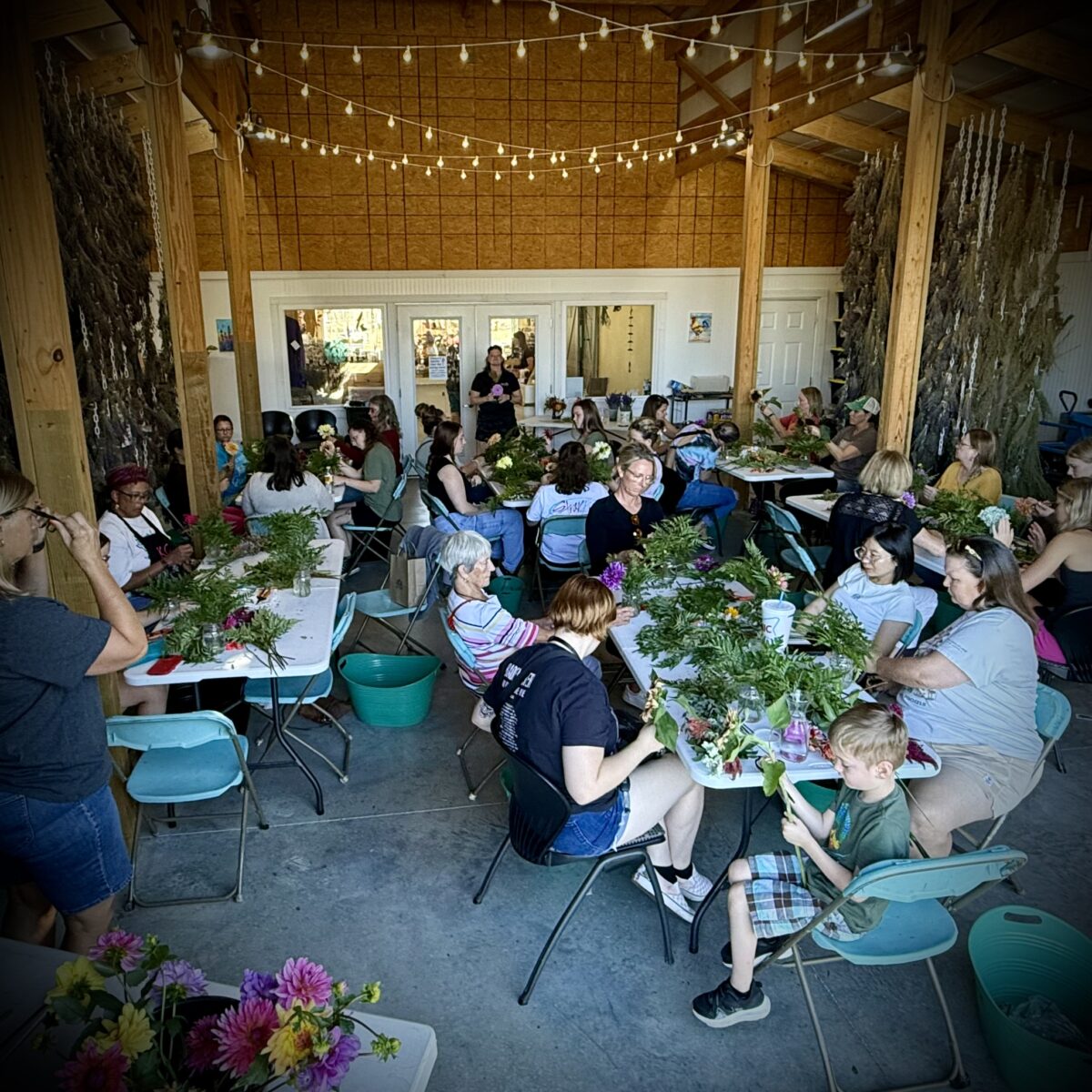 A group gathers in the lavender drying room for a flower arranging class.