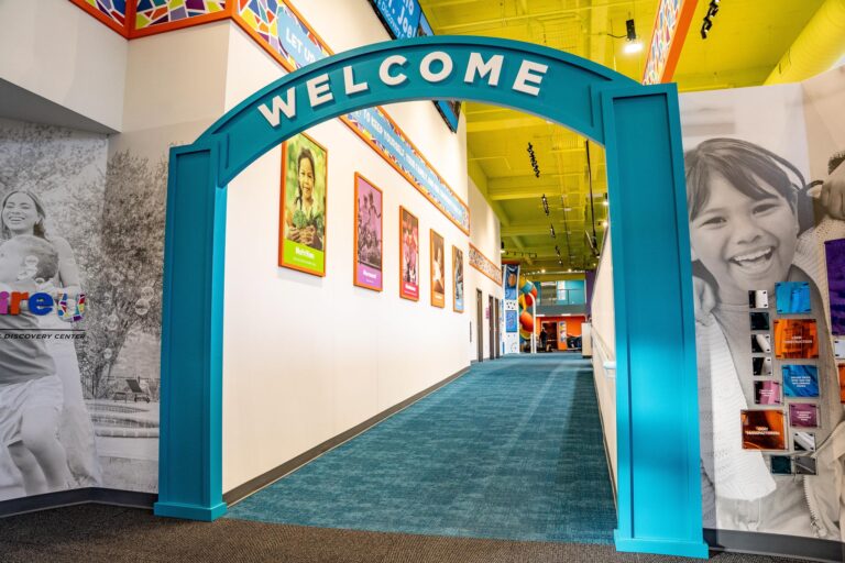 A blue arch with "welcome" over the top of it leading down a hallway.